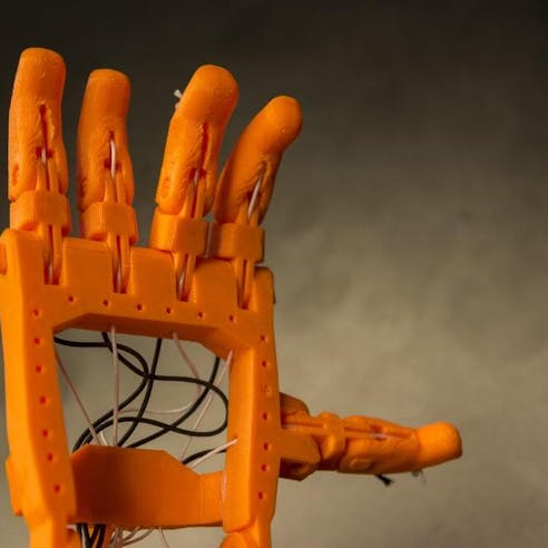 Orange 3D printed prosthetic hand. Image Credit: Shutterstock.com/Photo Oz
