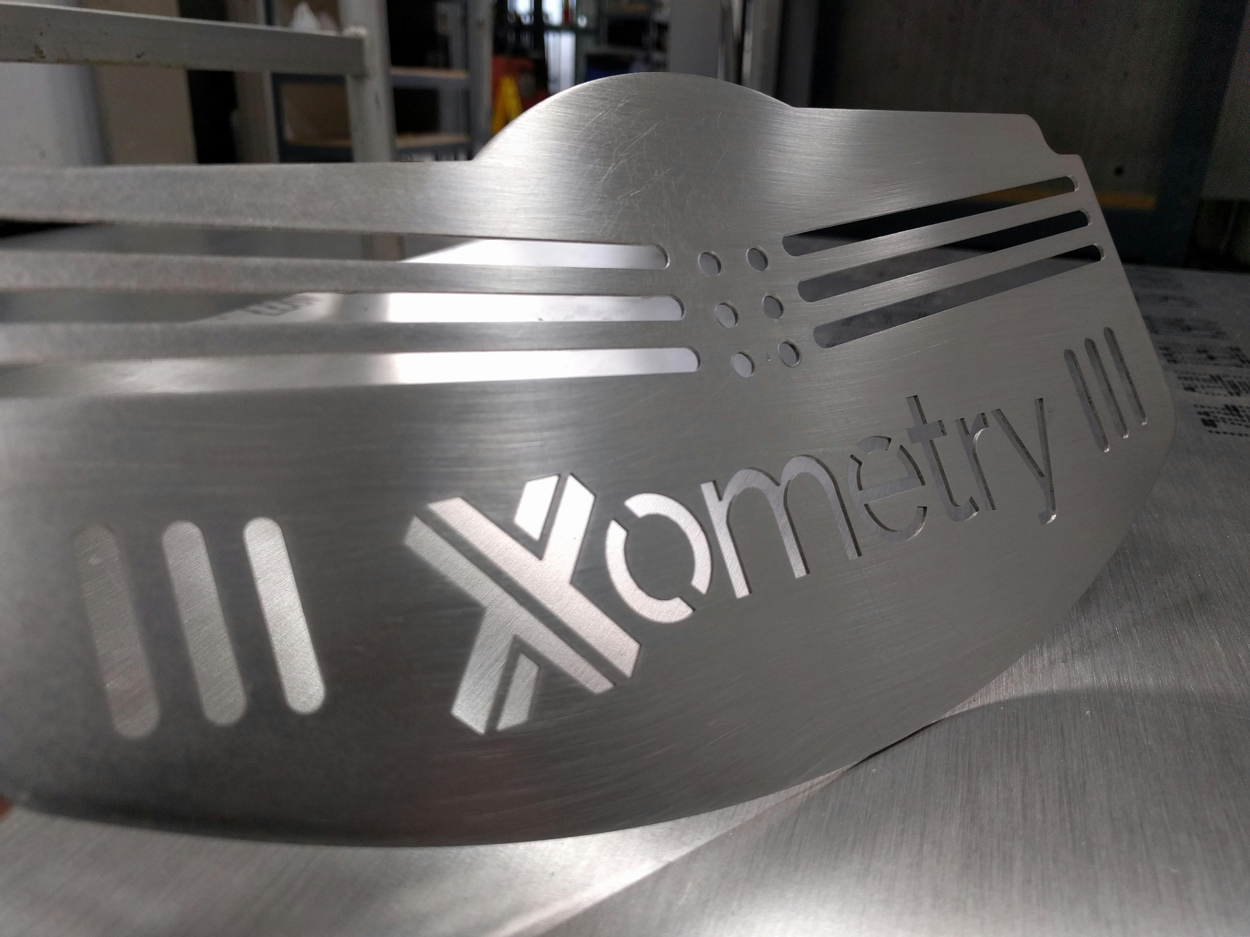 Sheet metal laser cut and punched plate with Xometry logo