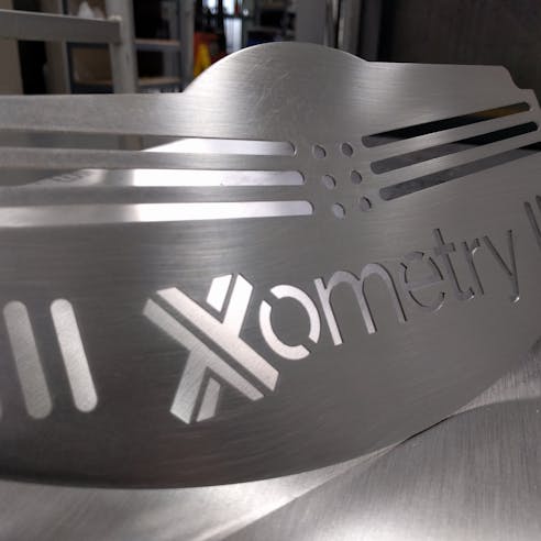 Sheet metal laser cut and punched plate with Xometry logo