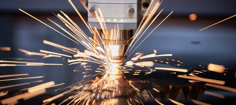 A laser cutting machine generates sparks as it cuts into metal.