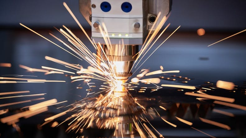 A laser cutting machine in operation generating sparks as it cuts into metal.