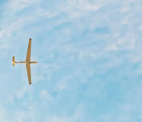 A glider towed by a super cub airplane in the sky