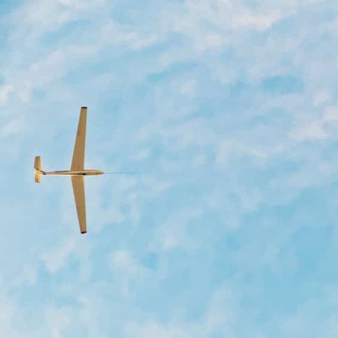 A glider towed by a super cub airplane in the sky