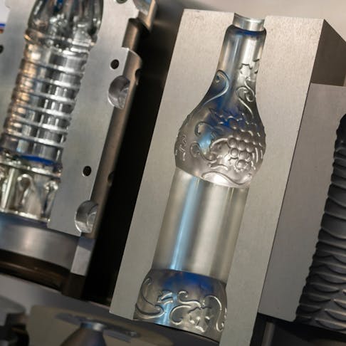 PET bottles being produced in a blow molding machine. Image Credit: MOLPIX/Shutterstock.com