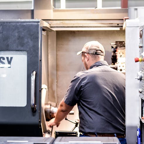 A CNC machinist using a live tooling lathe