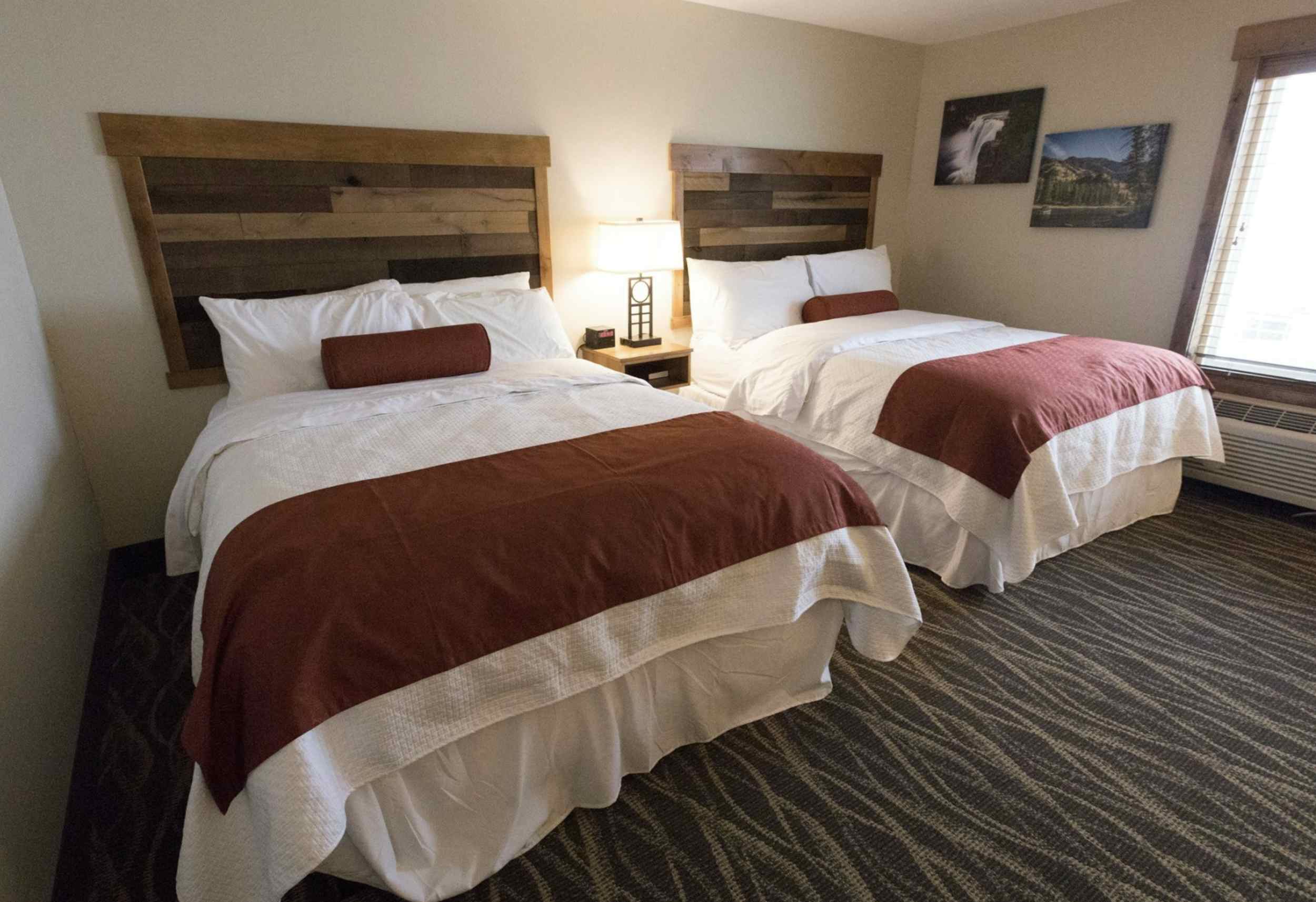 Photo from the inside of one of the rooms containing two beds side by side, with a window in the corner looking outward.