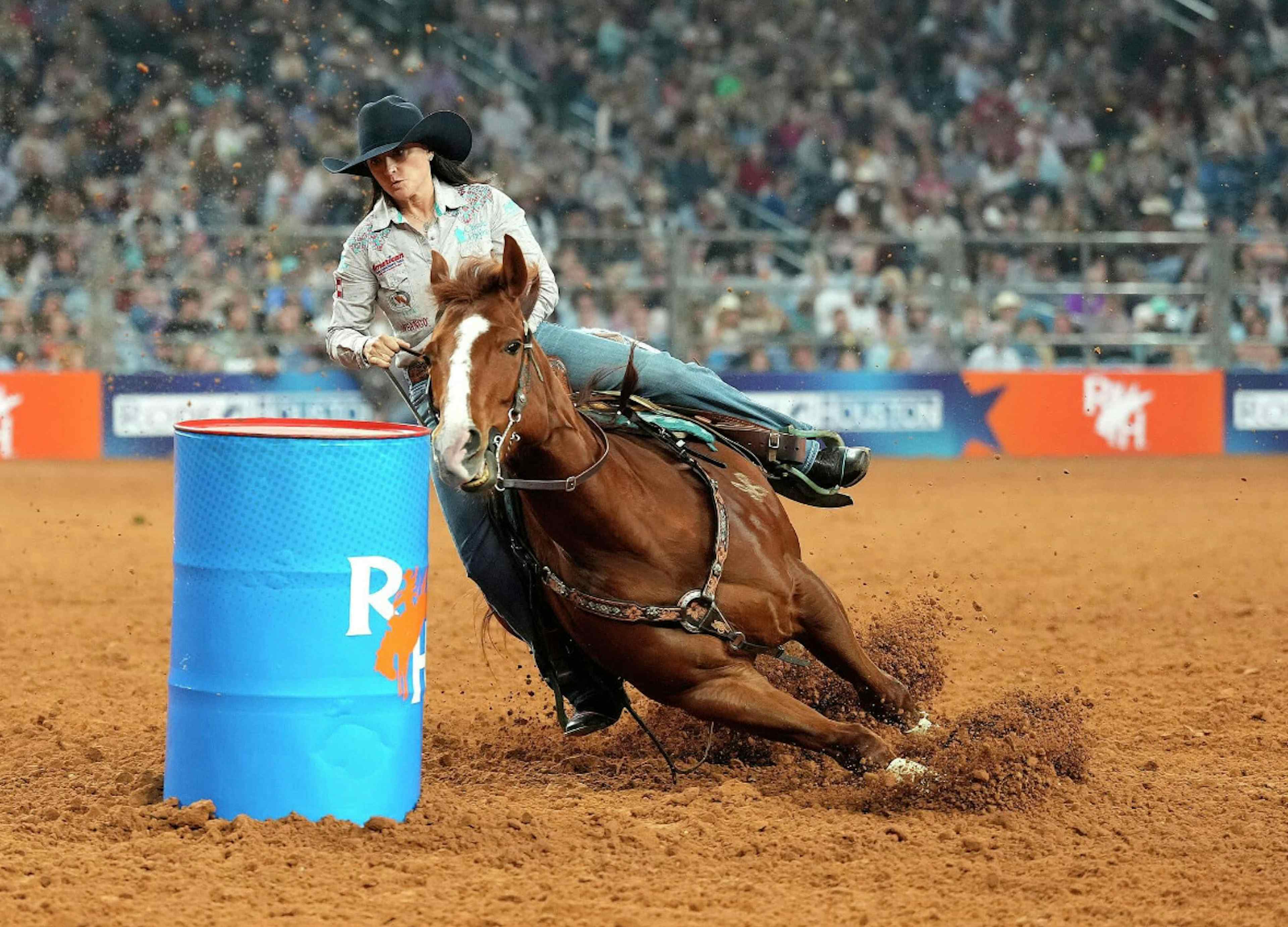 Woman riding a horse around a barrel at the rodeo