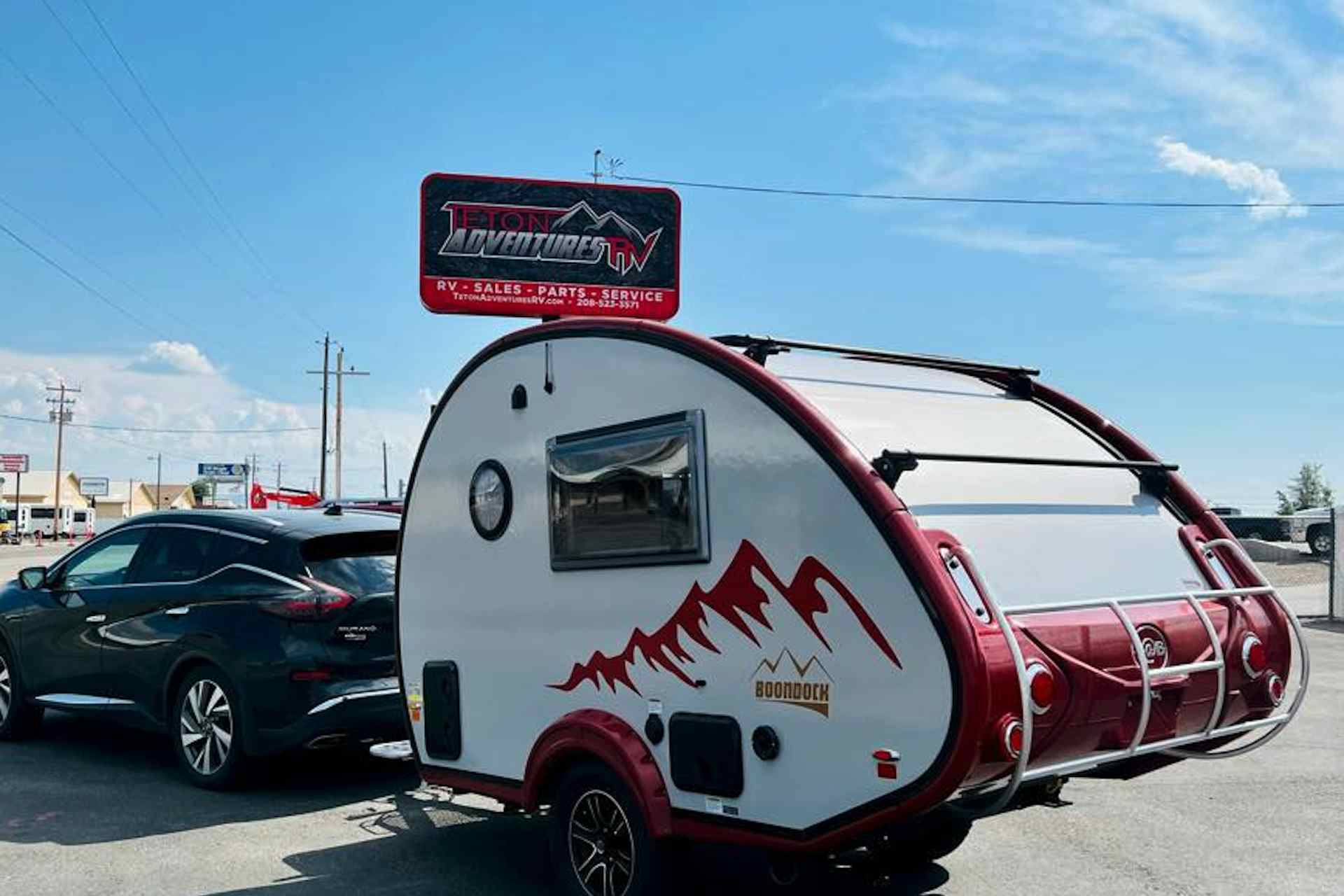 Car pulling a tralier from Teton Adventures RV in parking lot.