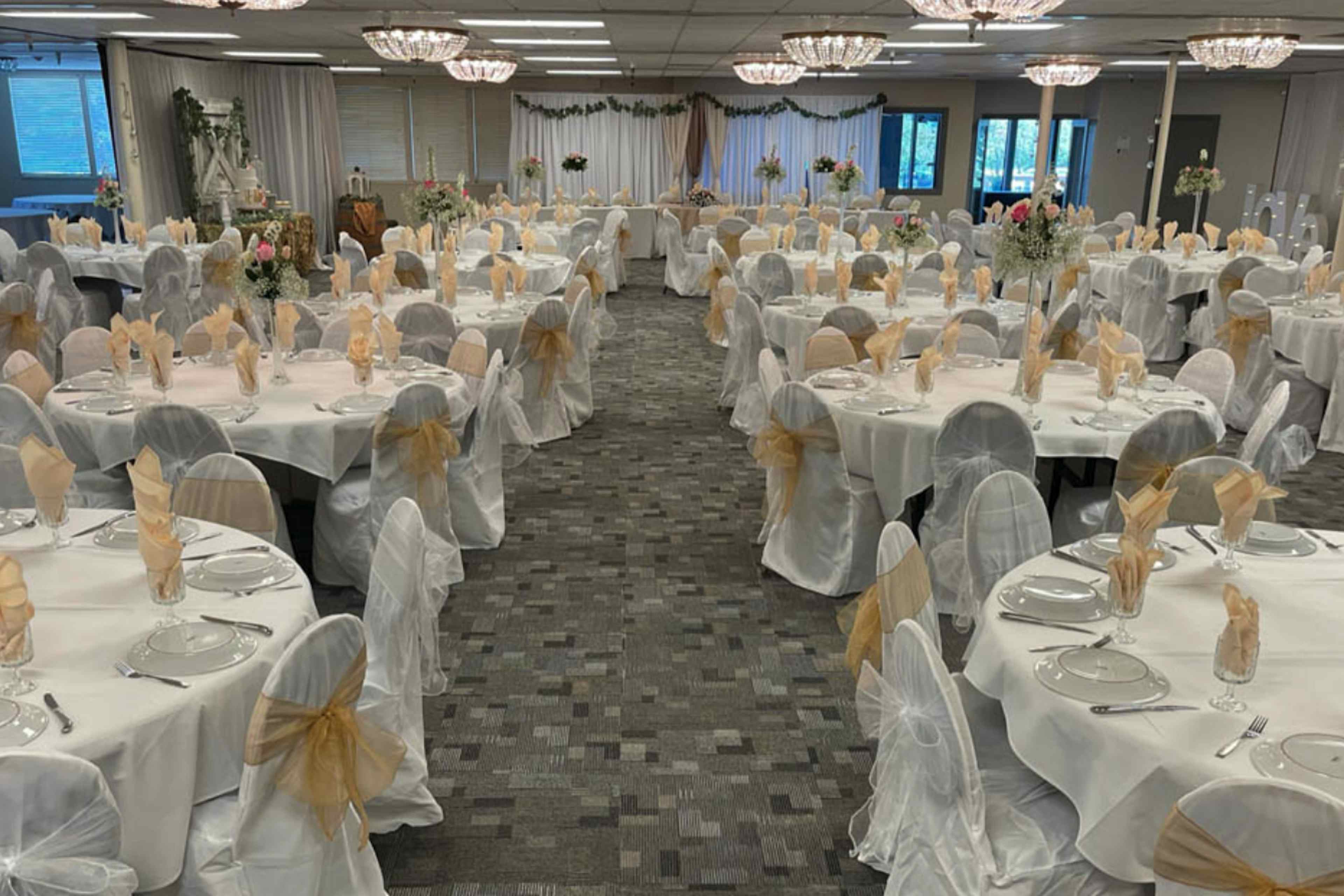 Multiple tables and chairs are arranged, adorned with plates, cups, and silverware, in preparation for a reception in Idaho Falls, Idaho.