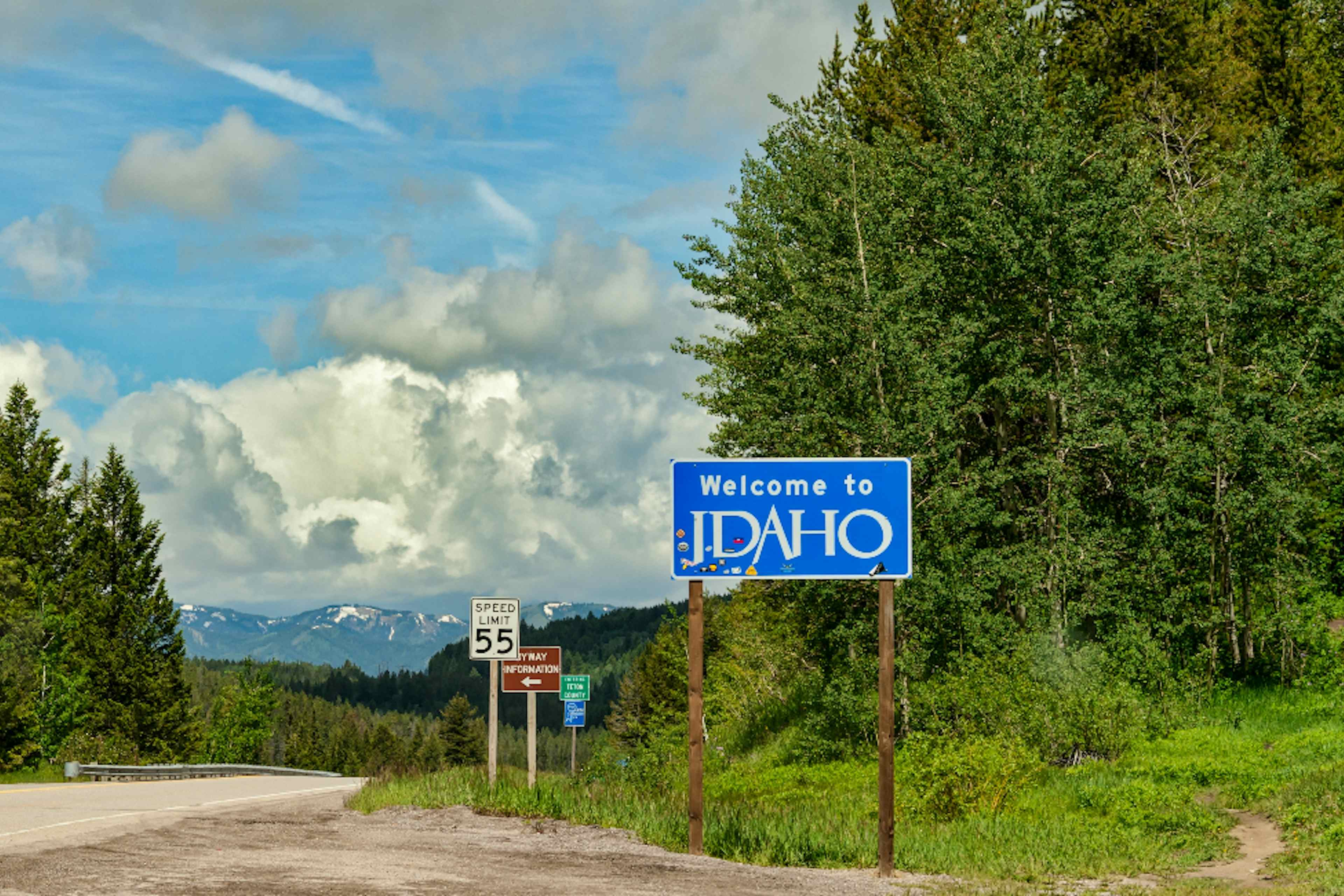 Idaho's state marker between Idaho and Wyoming under blue skies.