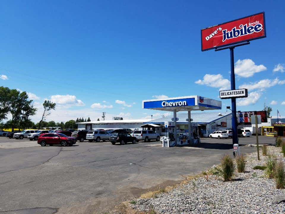 Many vehicles parked outside of Dave's Jubilee Market of Ashton of the Yellowstone Teton Territory, grabbing groceries and gas all at a cheap price.