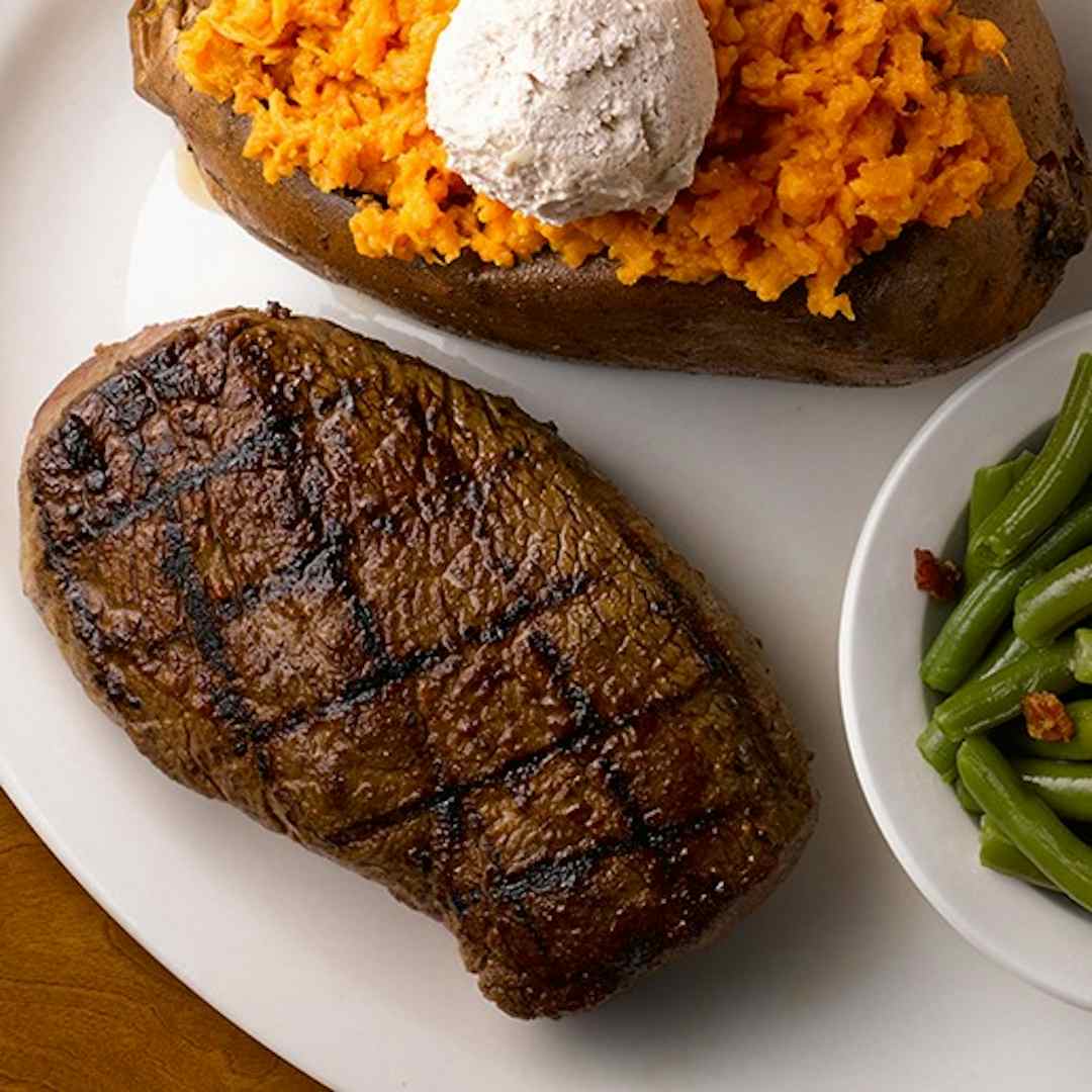 Hefty flame grilled steak served alongside sweet potato and green beans, featured at Texas Roadhouse in Idaho Falls, Idaho inside the Yellowstone Teton Territory