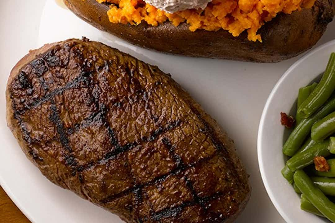 Hefty flame grilled steak served alongside sweet potato and green beans, featured at Texas Roadhouse in Idaho Falls, Idaho inside the Yellowstone Teton Territory