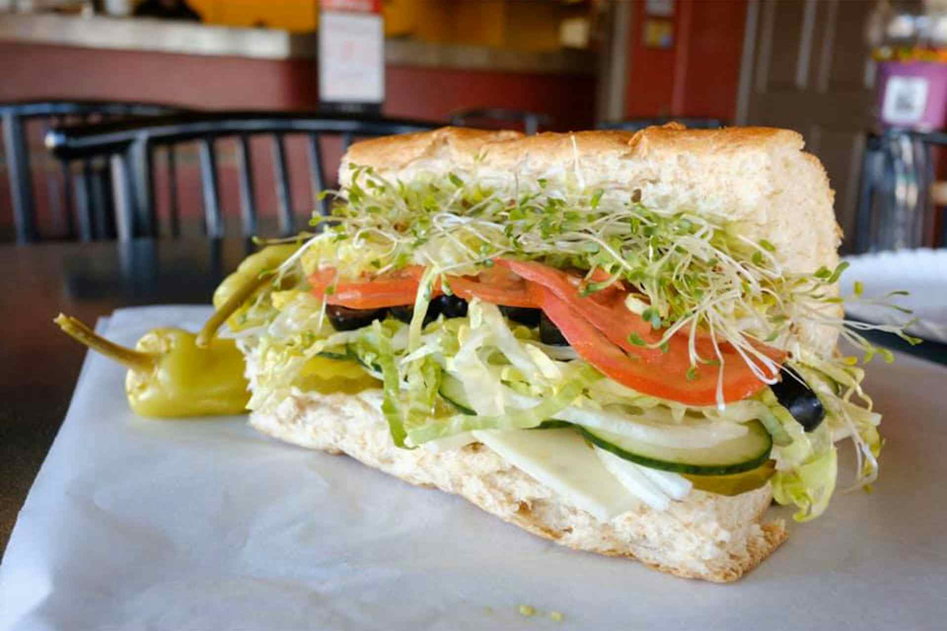 Fresh-made sandwich with pickles, tomatoes, and a hefty amount of greens served at the Sandwich Tree in Idaho Falls, Idaho of the Yellowstone Teton Territory
