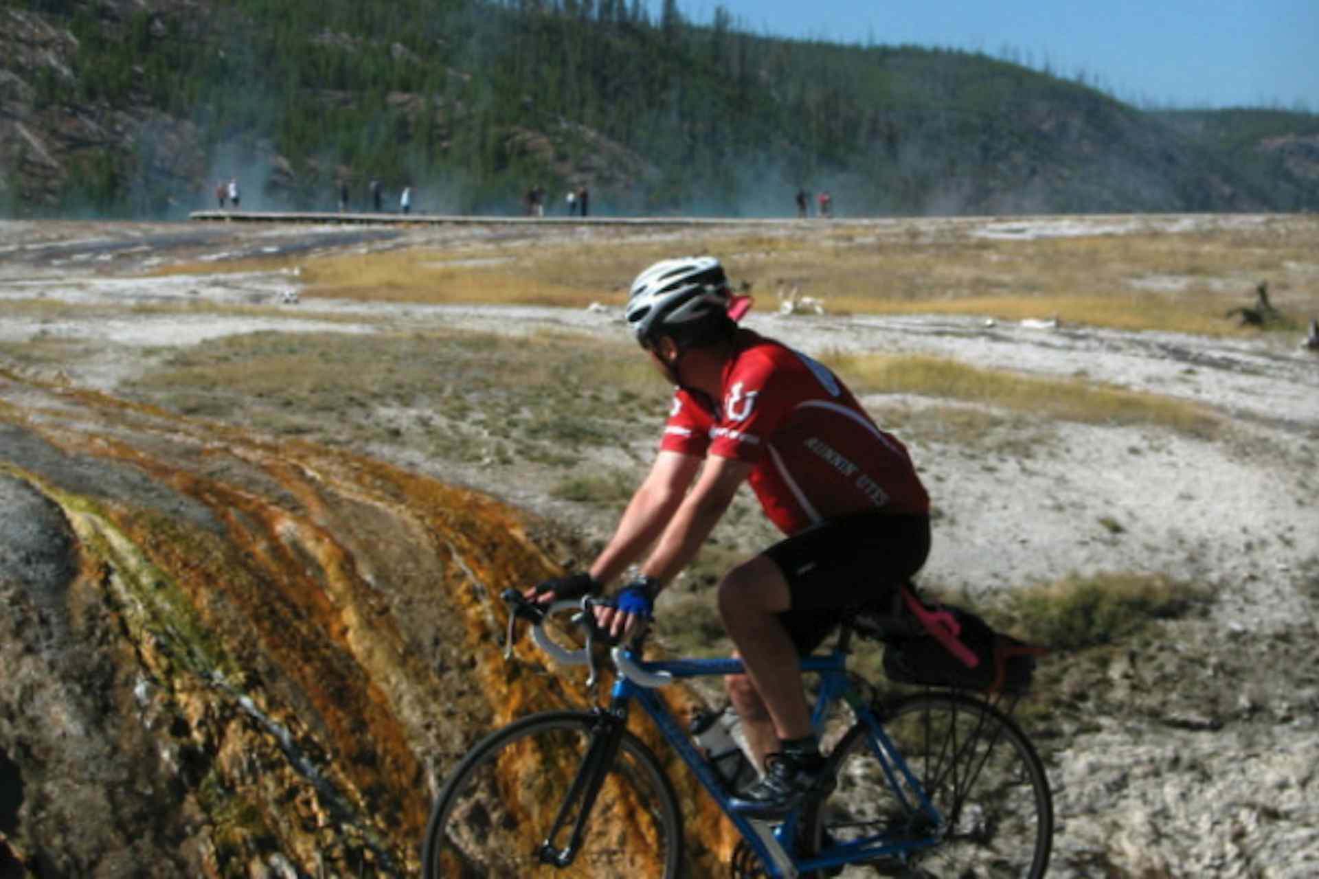 Cyclist next to Old Faithful in Yellowstone National Park in Yellowstone Teton Territory.