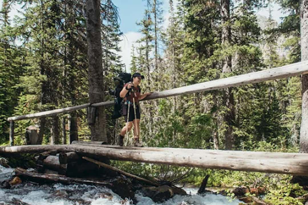 Hikers crosses a bridge on Upper Palisades Trail in Swan Valley, a part of Yellowstone Teton Territory.