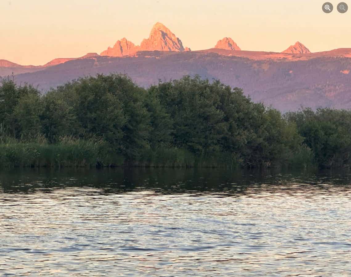 Picture of alpenglow on the Grand Teton and Teton Mountain Range from the Teton River in Teton Valley, a part of Eastern Idaho and Yellowstone Teton Territory.