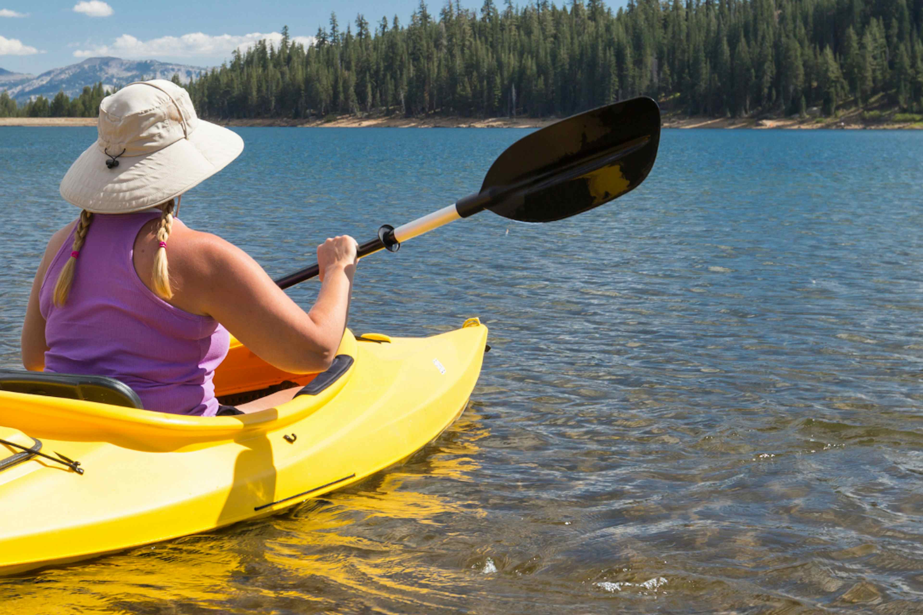 Woman paddleboards on Henry's Lake in Henry's Lake State Park in Island Park, ID in Yellowstone Teton Territory.