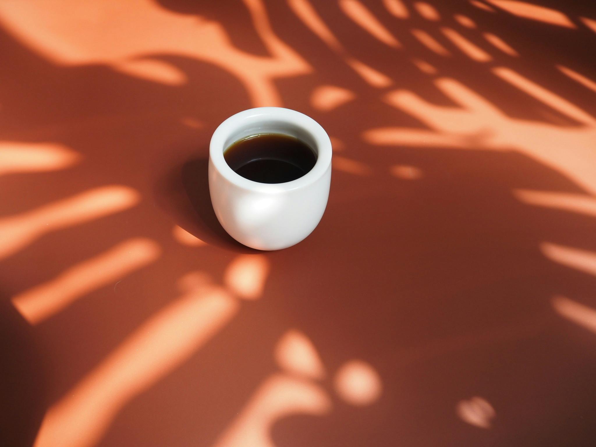 A cup of coffee in the shadows of plants