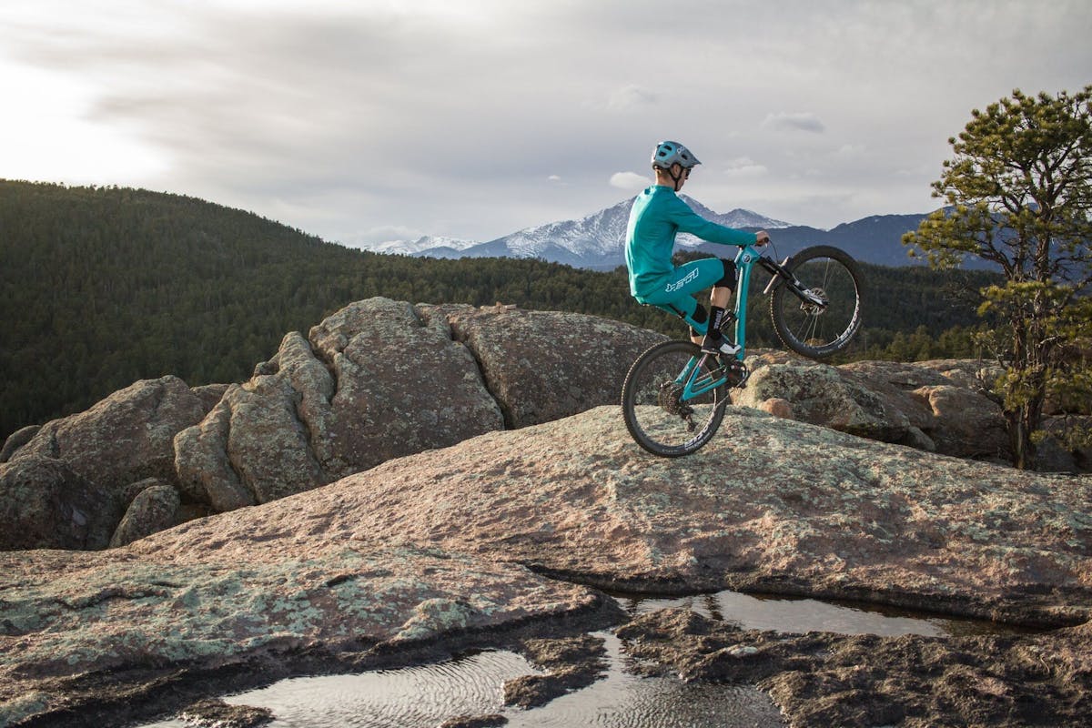 Tom Sampson riding a wheelie on a rock slab