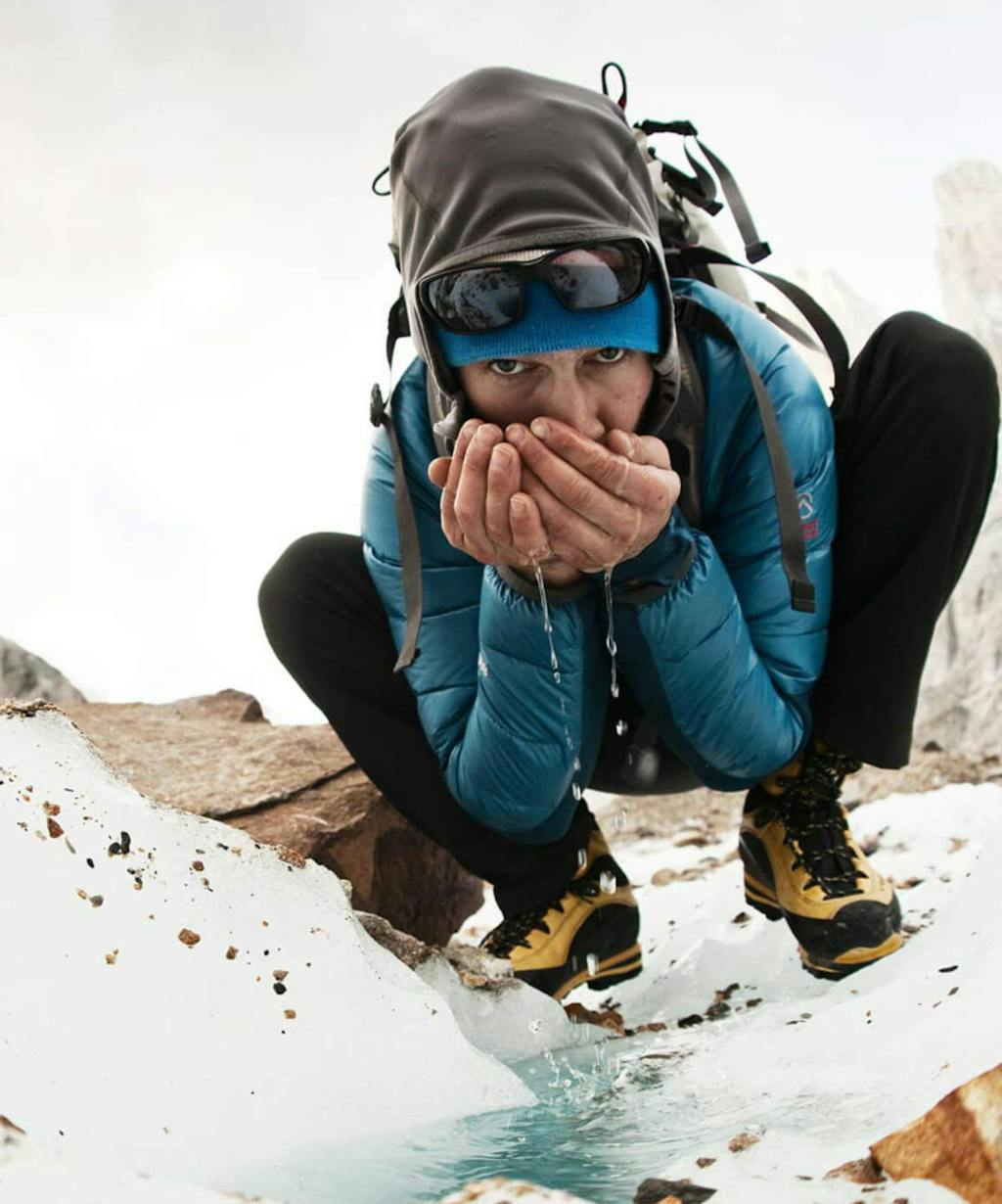 Renan Ozturk sipping water from glacial runoff