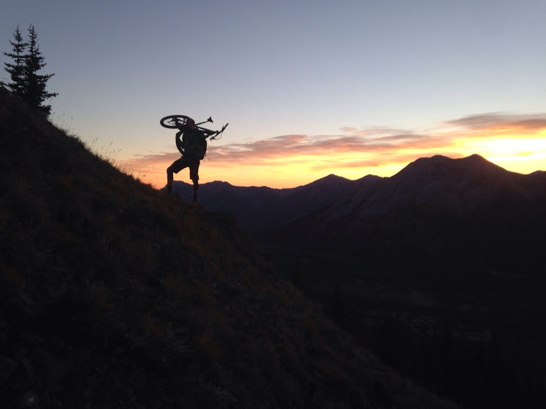 Reuben Krabbe hiking his bike in the alpine at sunset