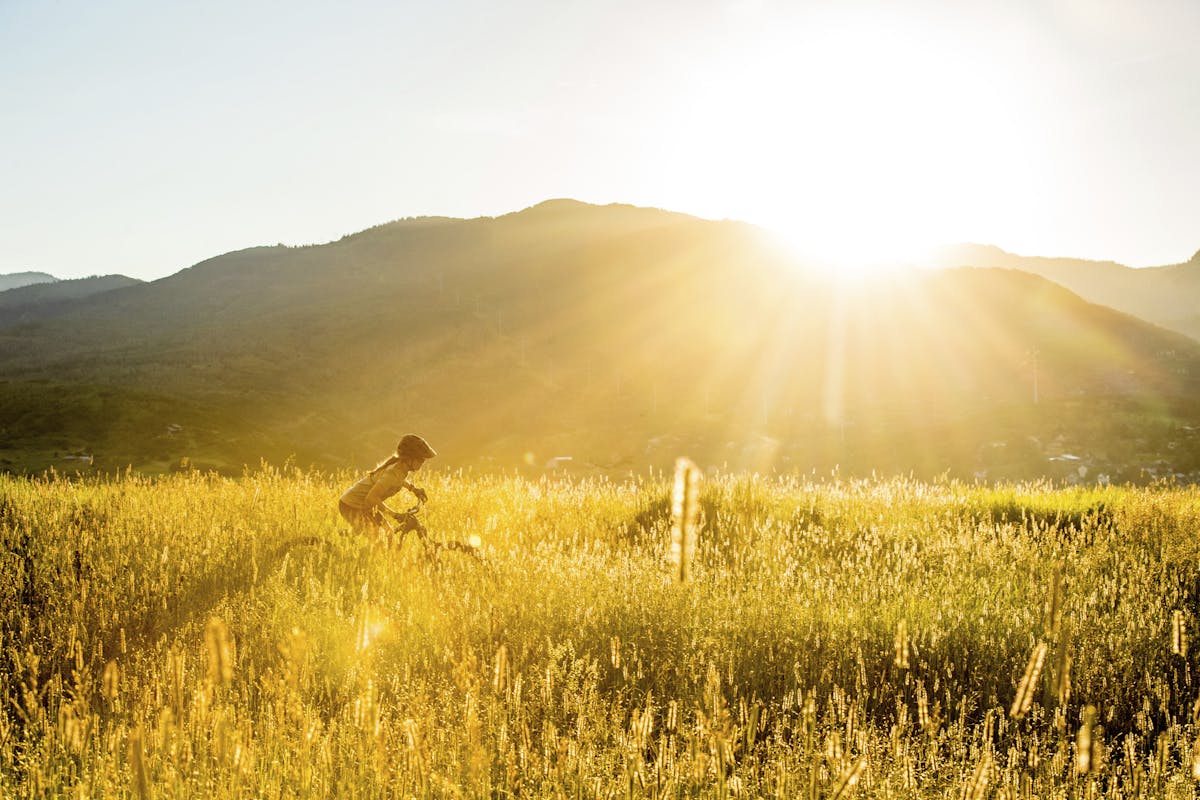 Britt Greer riding through a grassy field at sunset