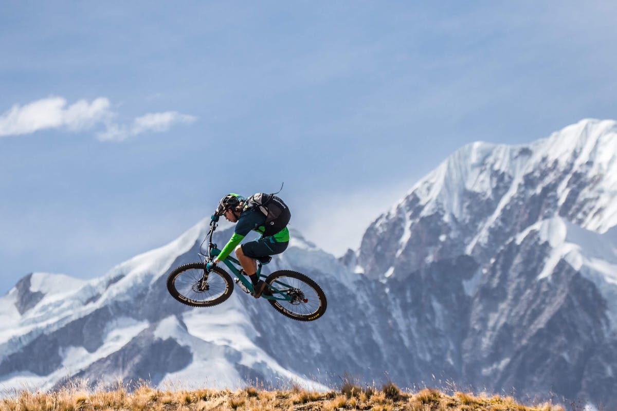 Joey Schusler hitting a jump with largoe Bolivian peaks in the background