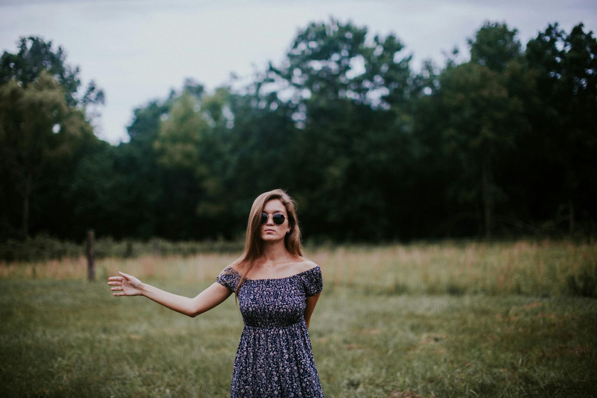 A woman, in a field, pointing with her hand open