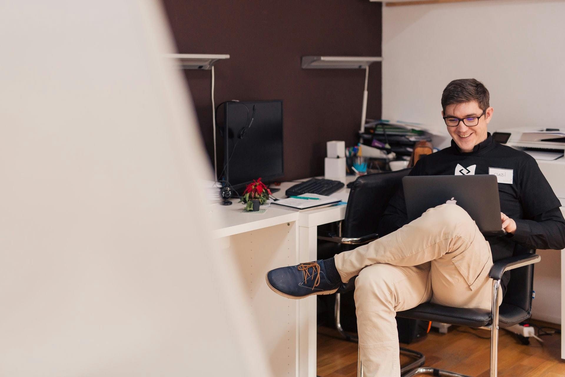 Smiling man, sitting near a desk with a laptop 