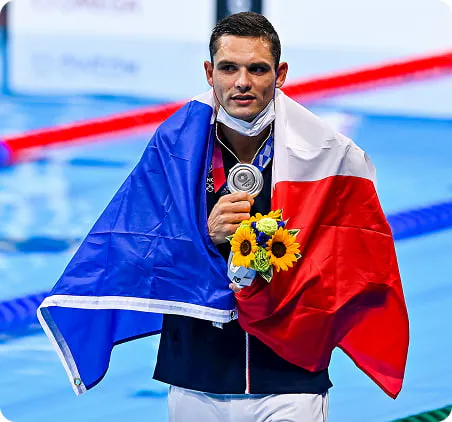 Florent Manaudou, couvert du drapeau français, après avoir remporté sa médaille d'argent à Tokyo.