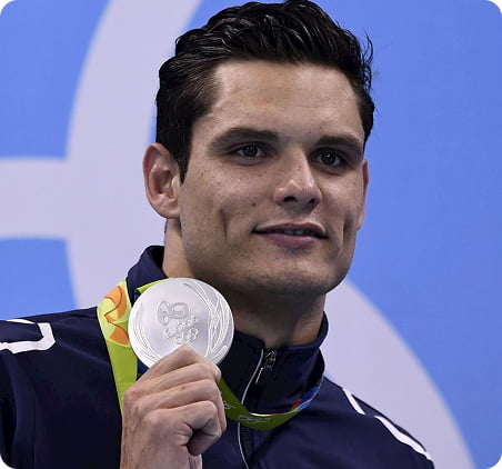 Portrait de Florent Manaudou souriant en montrant sa médaille d'argent.