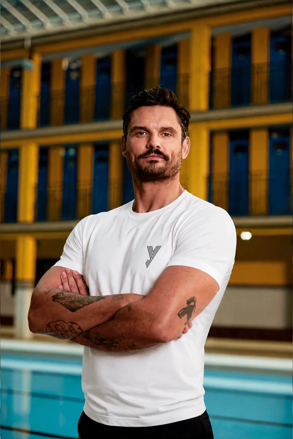 Portrait taille de Florent Manaudou, se tenant droit, les bras croisés et le regard sérieux.