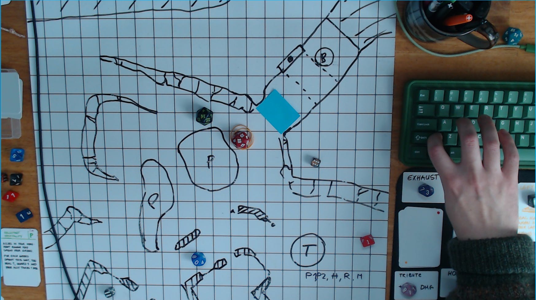 Screencap of a playtesting session showing the webcam view of a dry erase mat featuring a level layout and dice