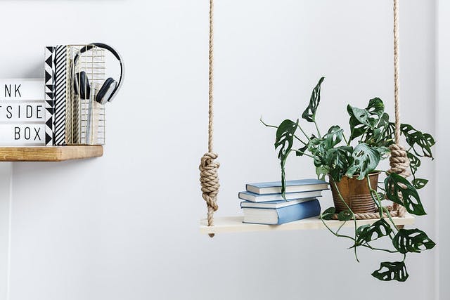 Photo of floating bookshelf next to a hanging shelf with books and a plant. 