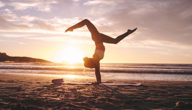 The picture shows a woman on a beach doing yoga