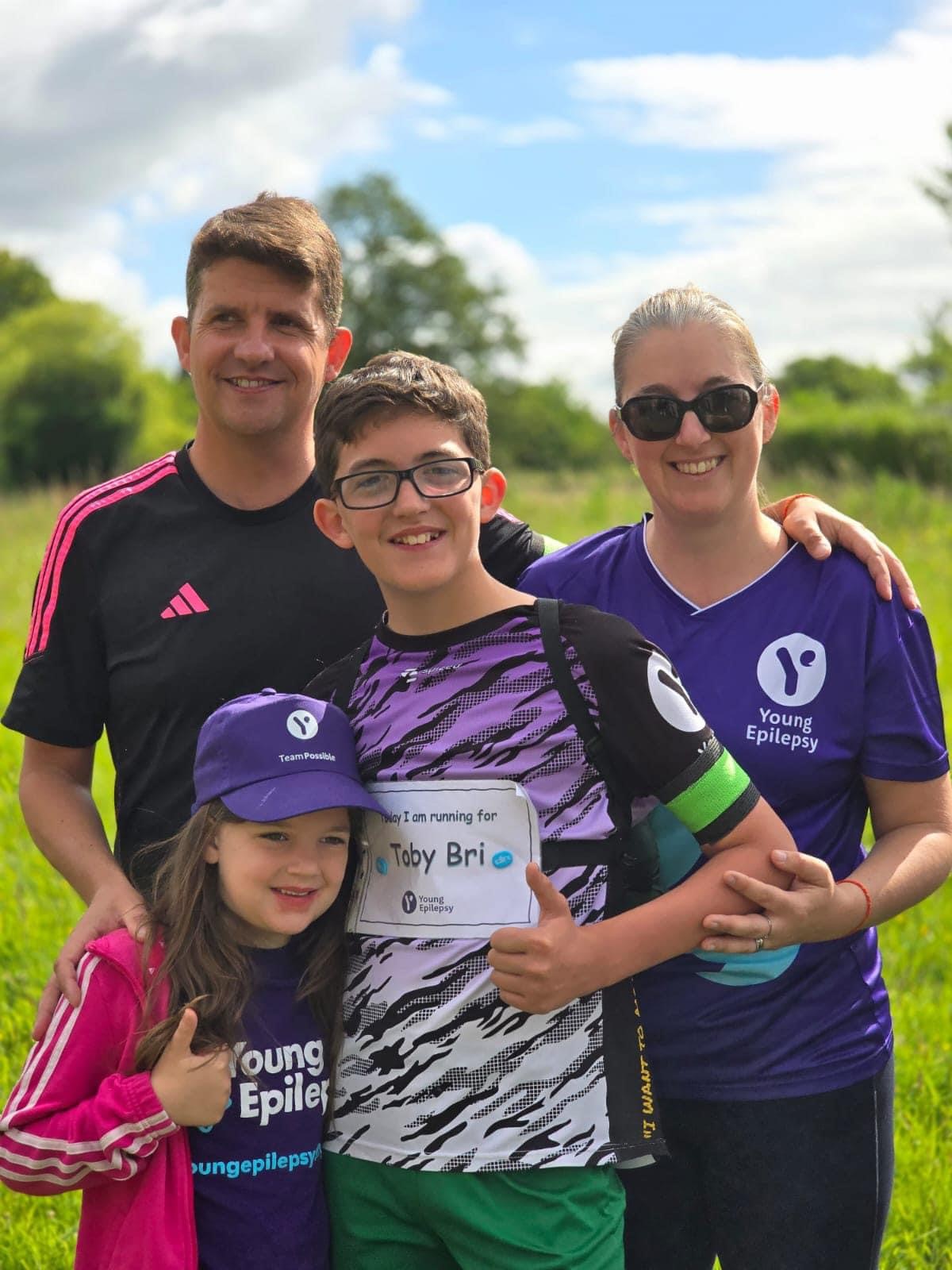 Zac smiling outdoors with his family. 