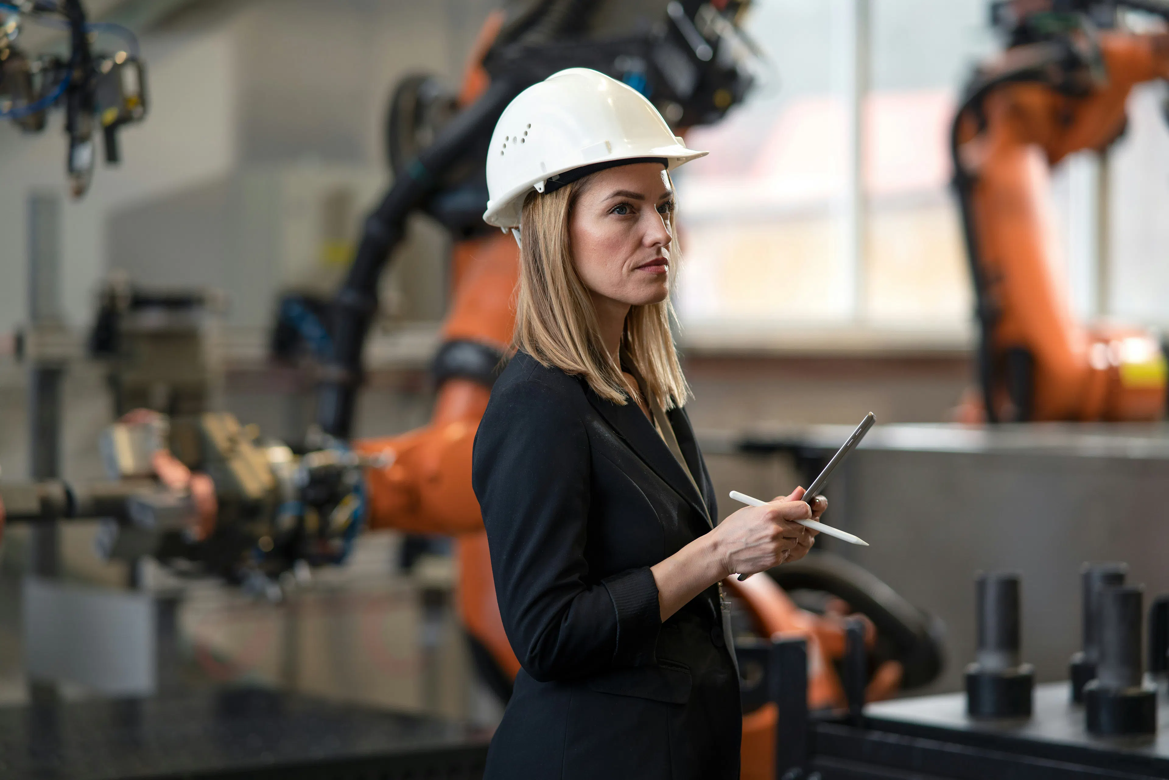 Woman in a hard hat holding a tablet in a factory