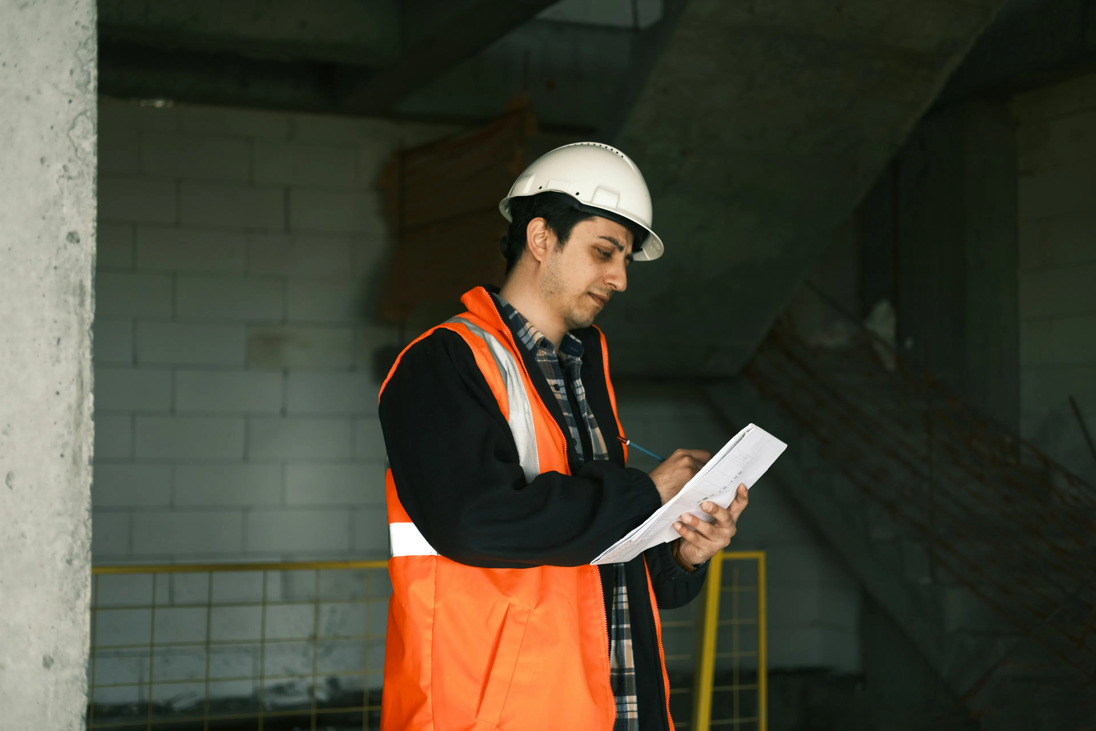 Construction worker in an orange safety vest reviewing paperwork