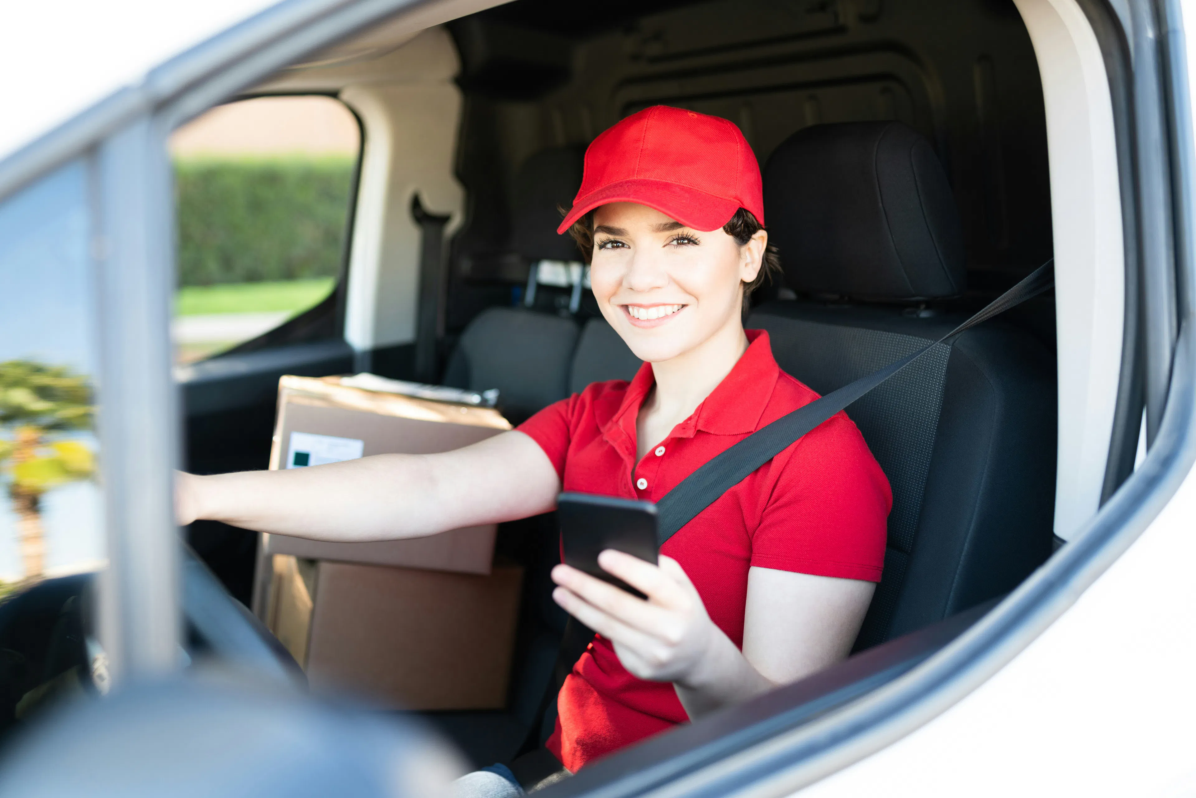 Delivery driver holding a smartphone inside her van