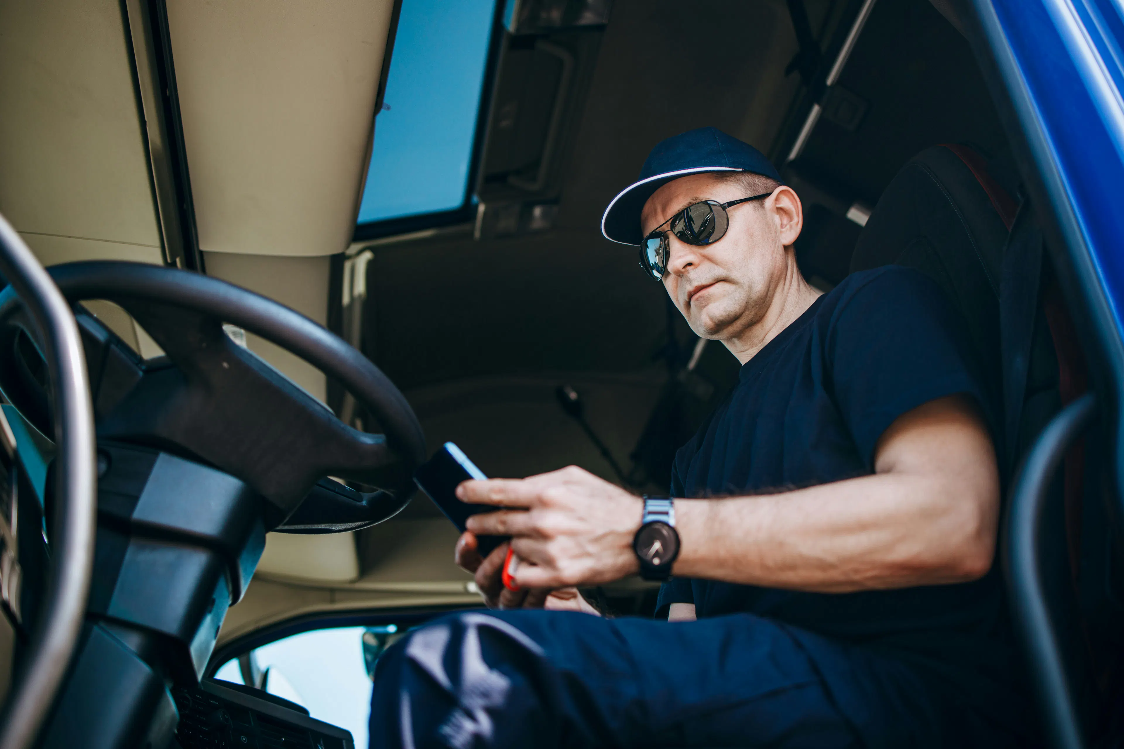 Truck driver checking phone in truck cab