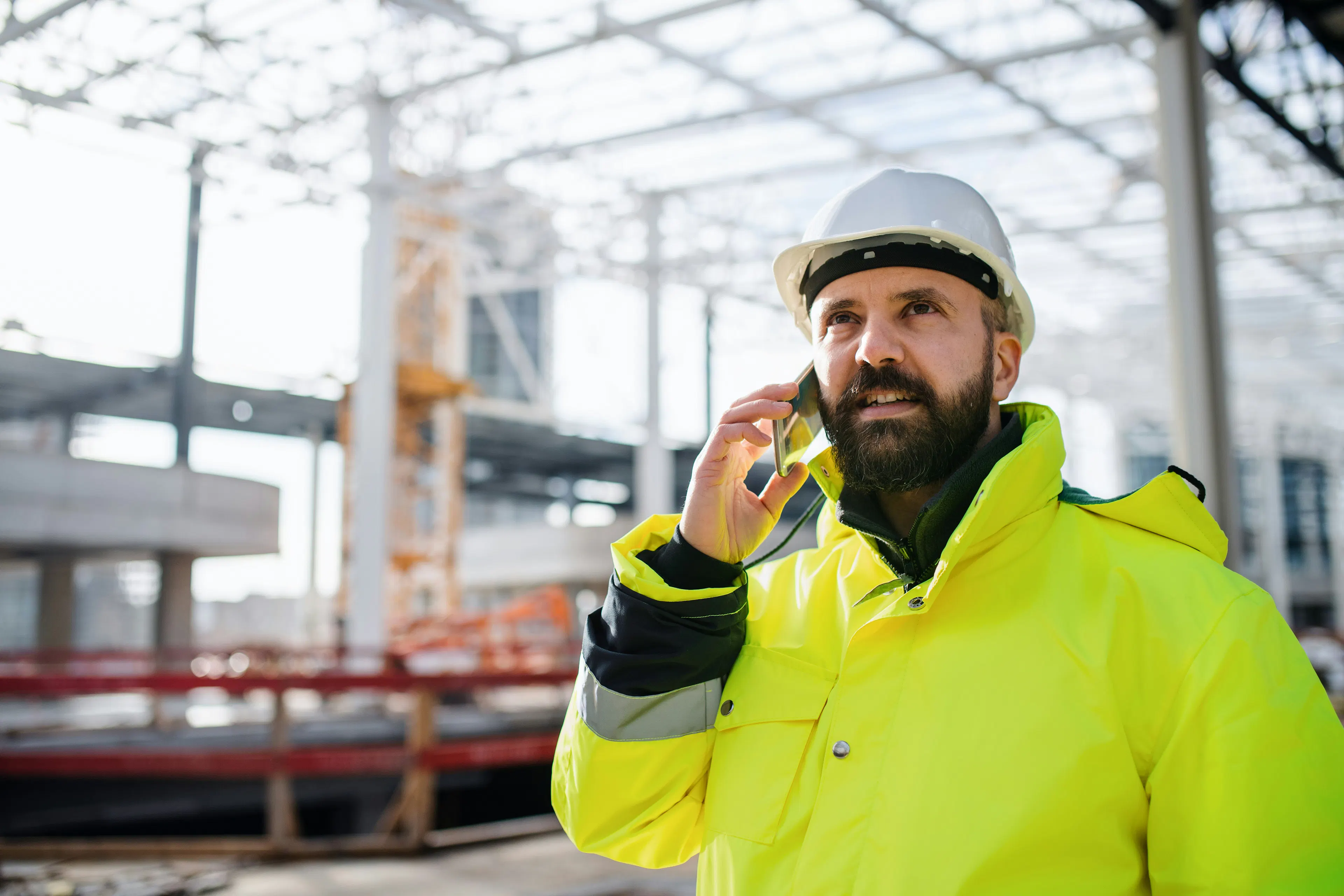 Construction worker making a call on a smartphone at a job site.