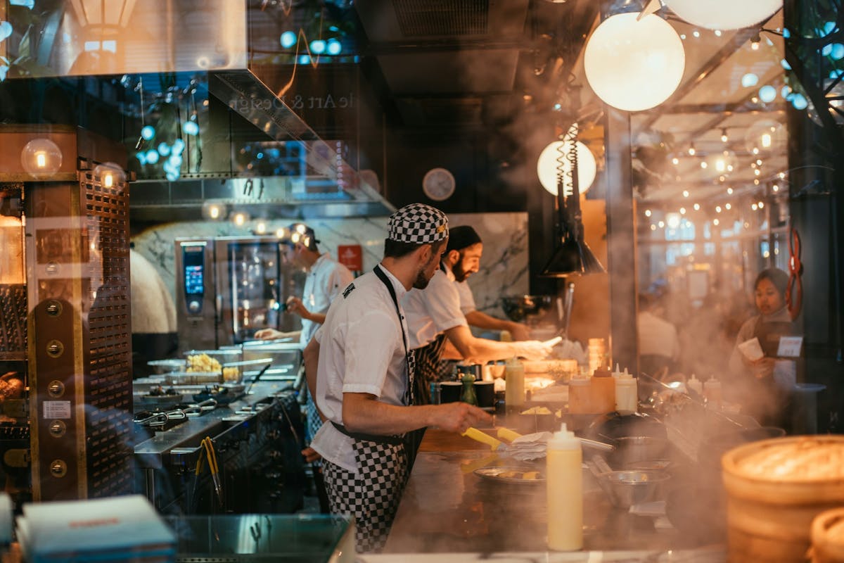 three chefs in a busy restaurant kitchen