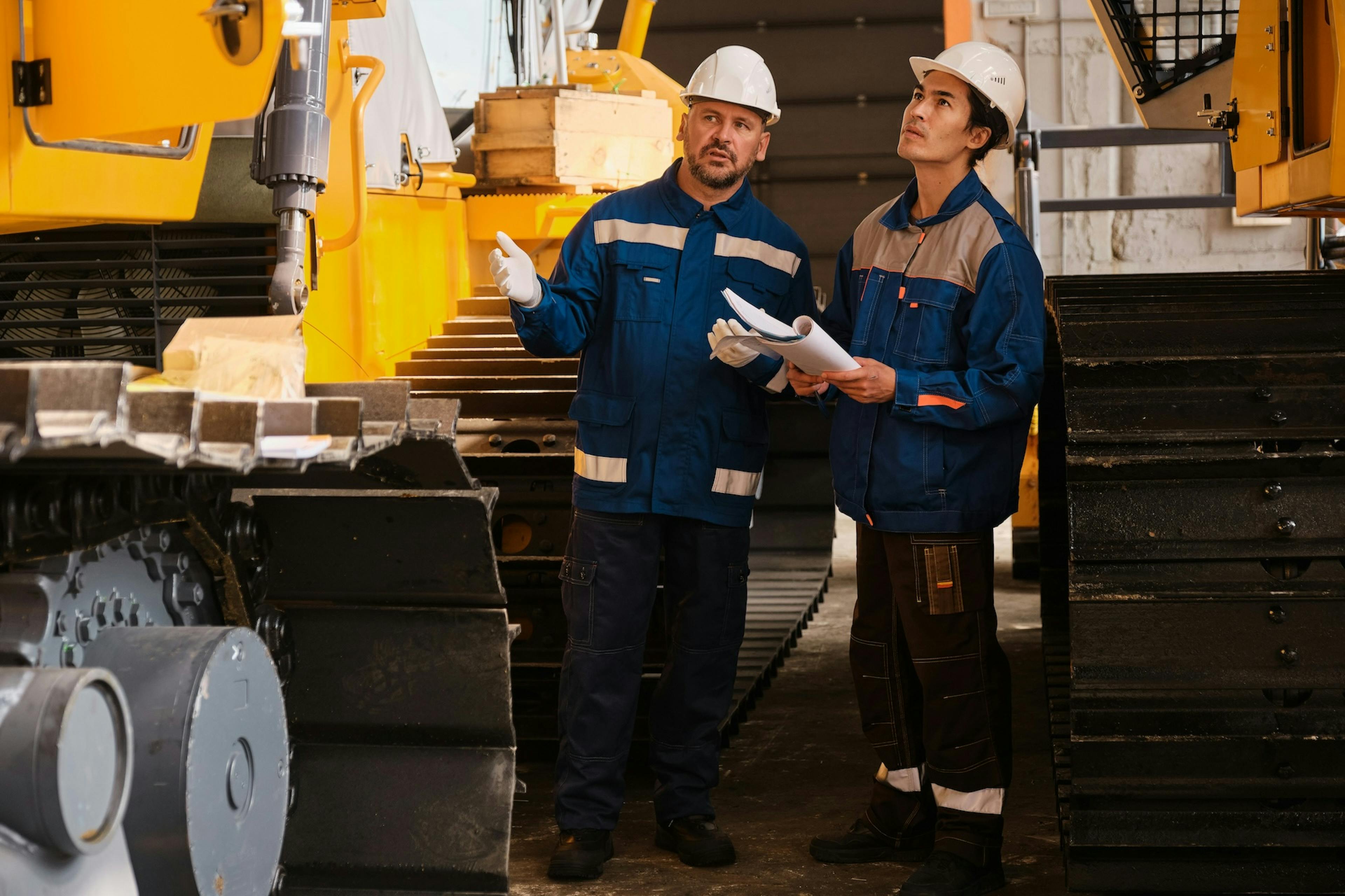 two construction workers having a conversation while inspecting machinery