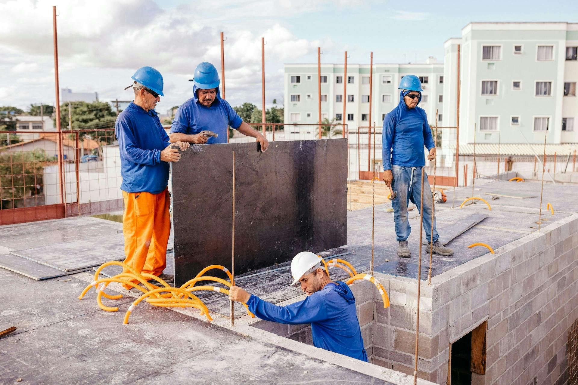 Four construction workers in blue shirts working on a rooftop