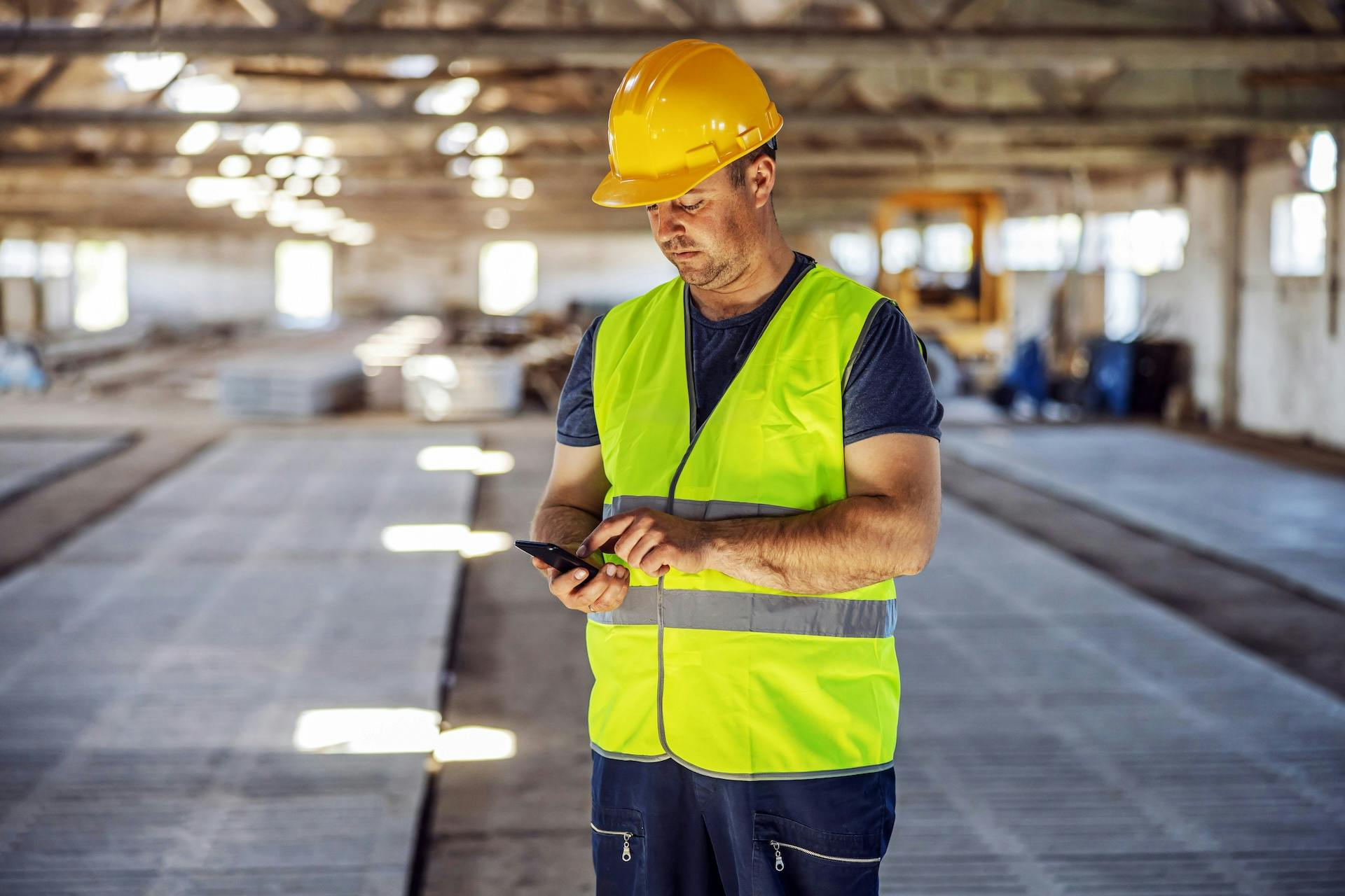 man at the construction site looking at the phone and typing