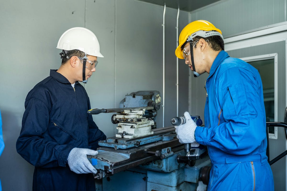 two workers, one holding a drill in his hands