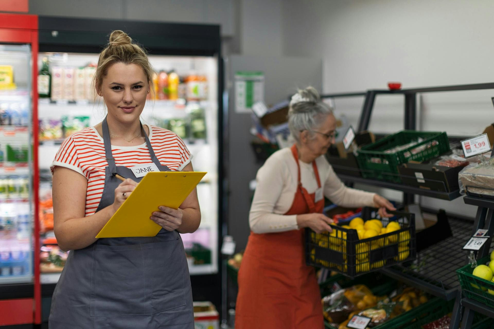 A retail worker wearing a name tag writing in a notebook