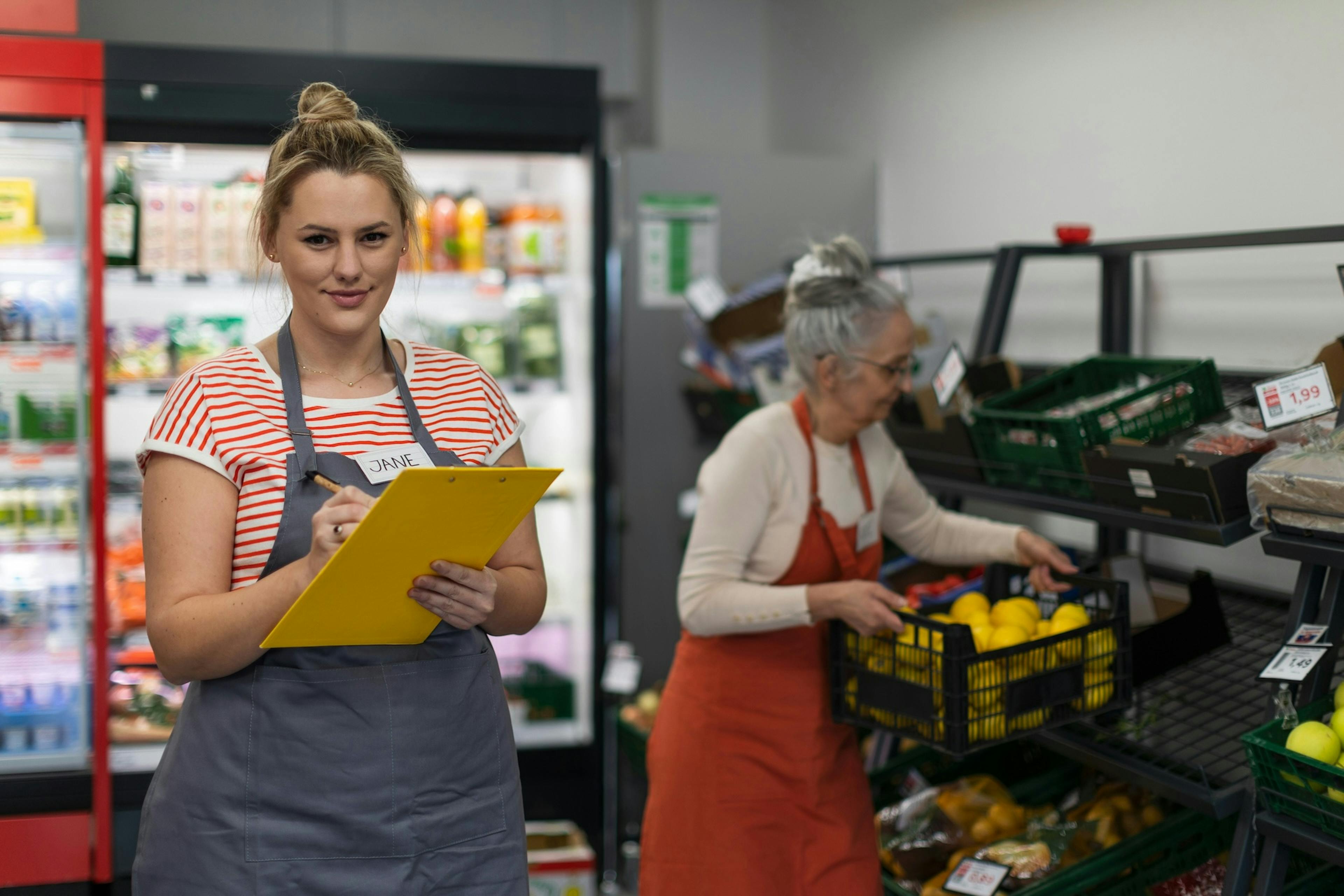 A retail worker wearing a name tag writing in a notebook