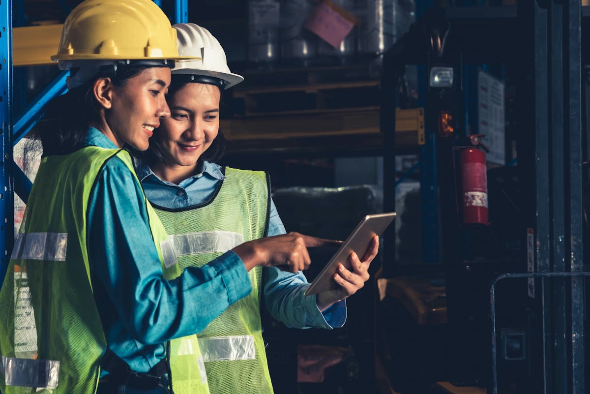 Two workers smiling while looking at the tablet